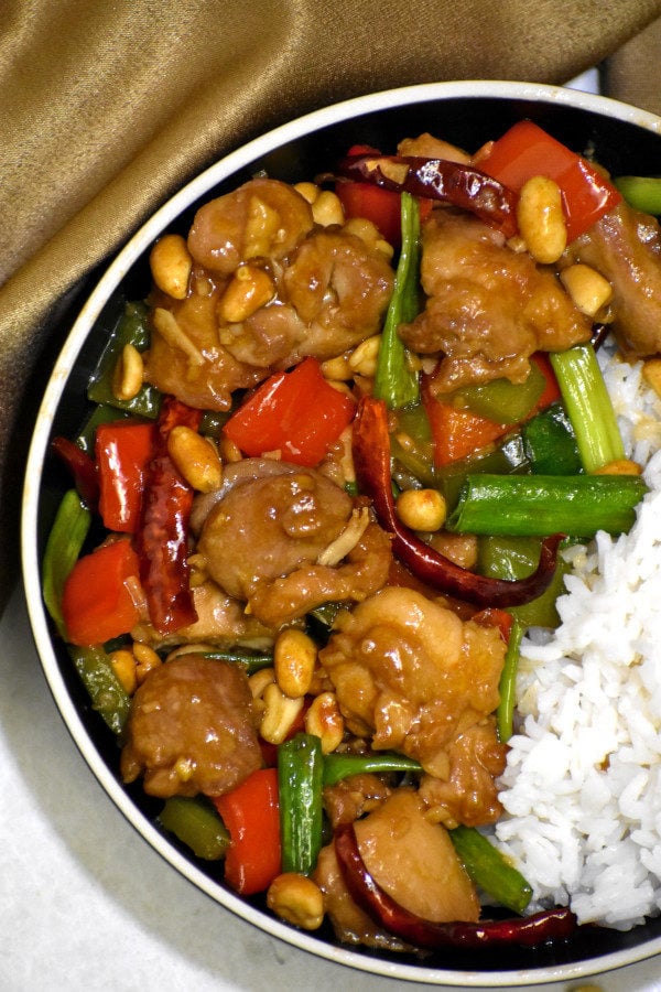 kung pao chicken in a black bowl with rice