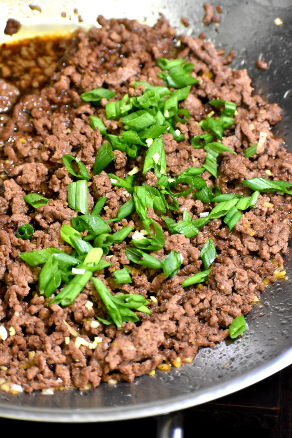 在一锅牛肉煎大蒜和姜切碎的葱补充道