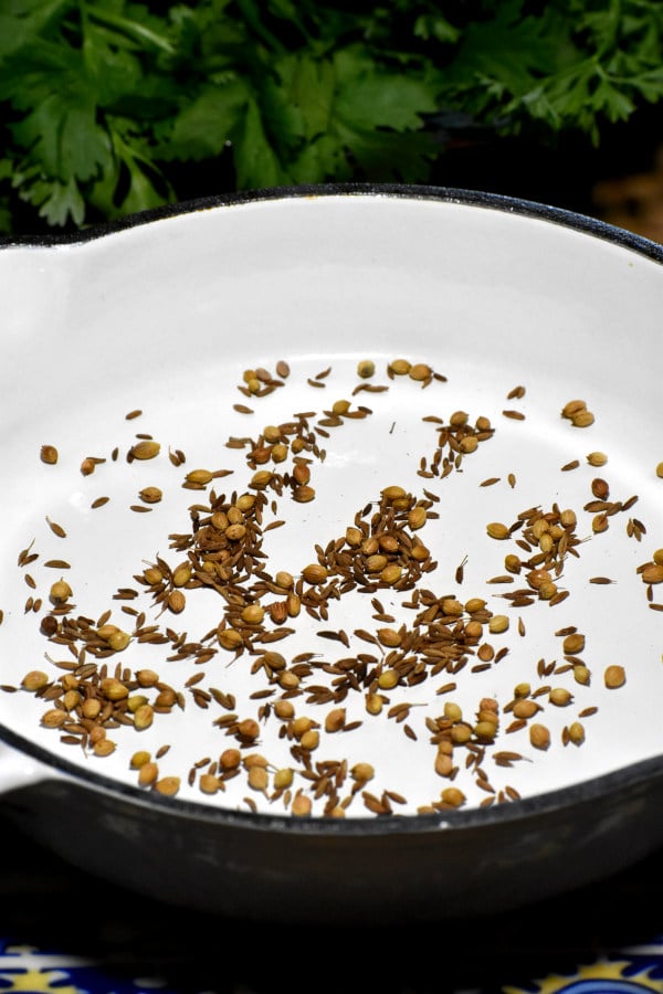 孜然和香菜籽在白色平底锅里烤