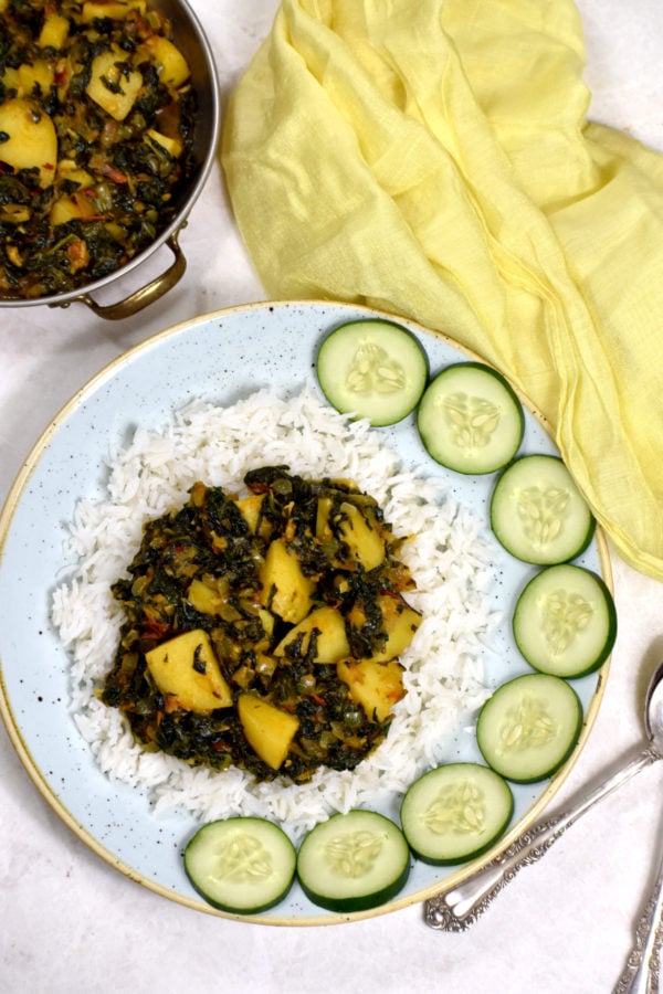 Aloo Palak铺在白米饭上，用黄瓜片装饰。