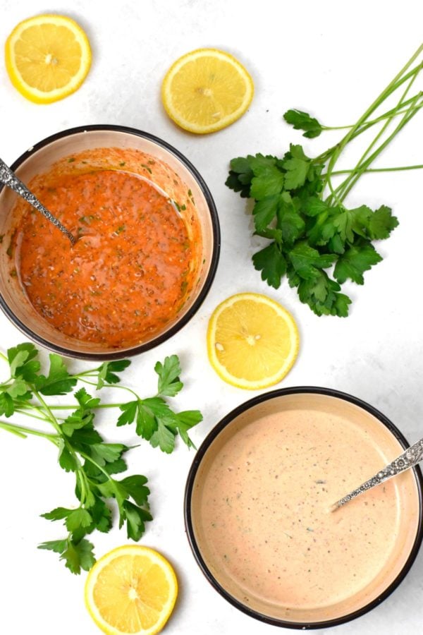Overhead shot of two bowls of remoulade variations, one red colored and one pink.